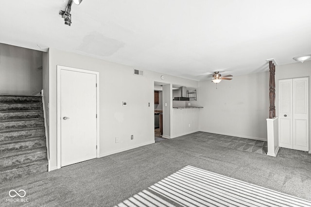 unfurnished living room featuring visible vents, a ceiling fan, baseboards, stairway, and dark carpet