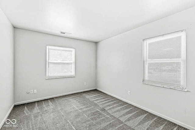 carpeted spare room featuring visible vents and baseboards