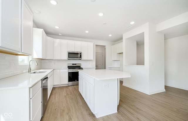 kitchen featuring white cabinetry, sink, a center island, stainless steel appliances, and light hardwood / wood-style flooring