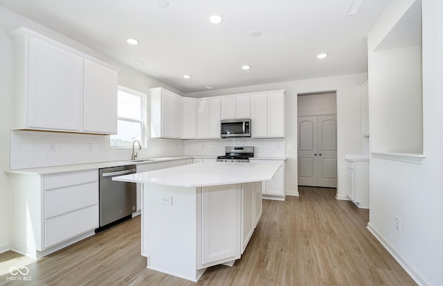 kitchen featuring light hardwood / wood-style flooring, stainless steel appliances, tasteful backsplash, white cabinets, and a kitchen island