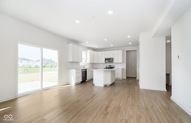 kitchen featuring white cabinetry, stainless steel appliances, a center island, and light wood-type flooring