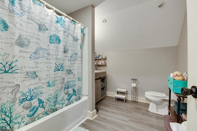 bathroom with baseboards, vaulted ceiling, toilet, wood finished floors, and shower / tub combo with curtain