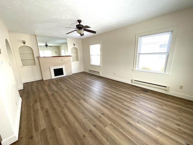 unfurnished living room featuring a textured ceiling, dark wood-type flooring, arched walkways, and a baseboard radiator