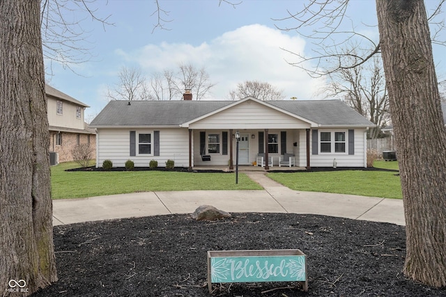 view of front of property featuring covered porch, a front lawn, a chimney, and cooling unit