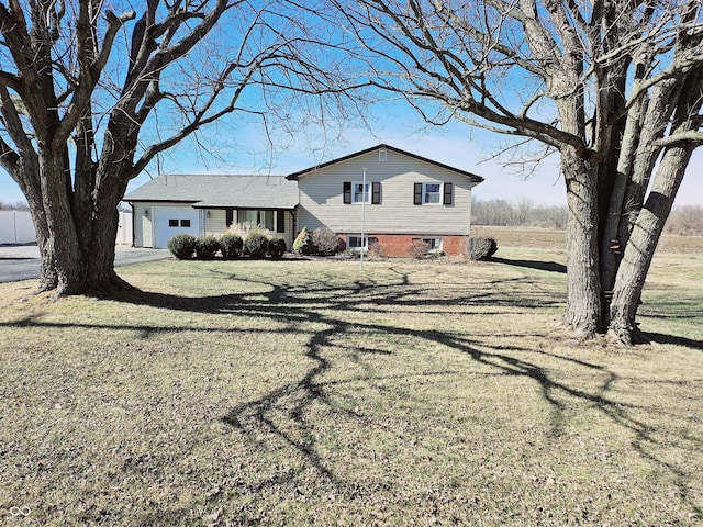 tri-level home featuring an attached garage, driveway, and a front yard