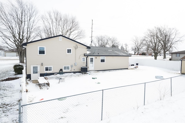 snow covered house with cooling unit and fence