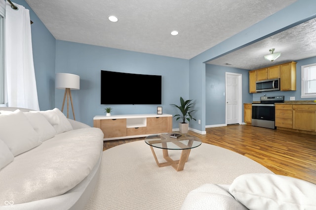 living area with a textured ceiling, recessed lighting, wood finished floors, and baseboards