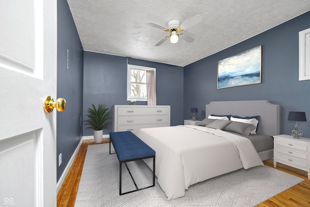 bedroom featuring a textured ceiling, ceiling fan, light wood-style flooring, and baseboards