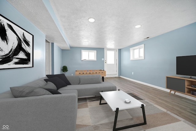 living room featuring baseboards, a textured ceiling, and light wood-style floors