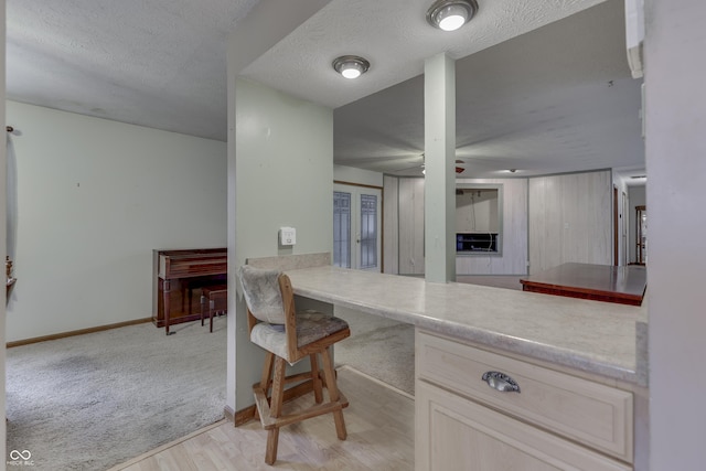 kitchen featuring french doors, ceiling fan, a textured ceiling, light carpet, and light brown cabinetry