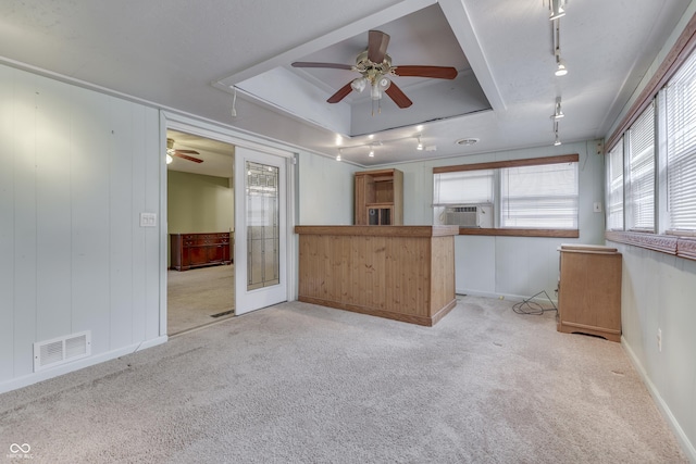 interior space featuring light carpet, track lighting, a tray ceiling, and cooling unit