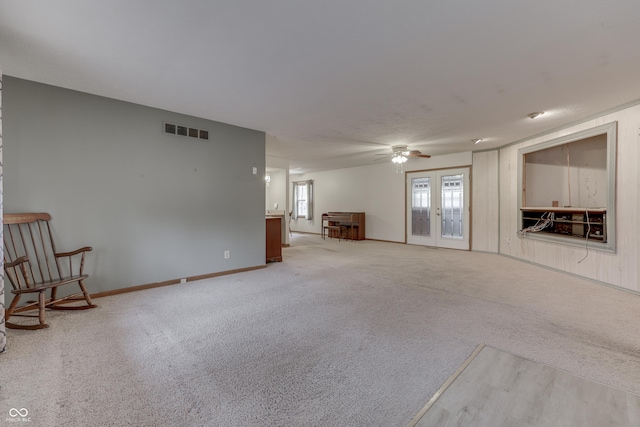 unfurnished living room with ceiling fan, carpet floors, and french doors