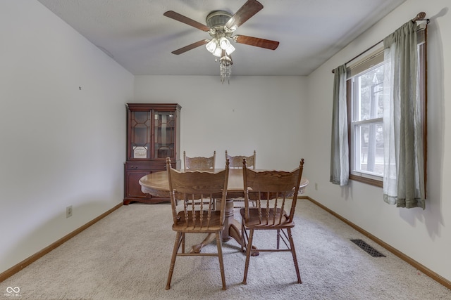 dining area featuring ceiling fan and light colored carpet