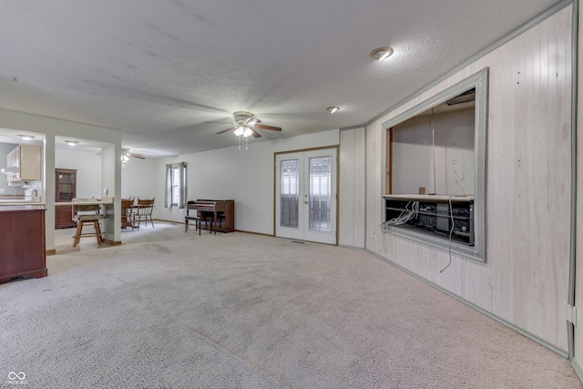 unfurnished living room with french doors, light carpet, a textured ceiling, and ceiling fan