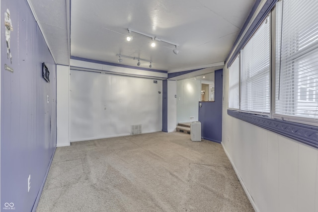 unfurnished room featuring rail lighting and light colored carpet