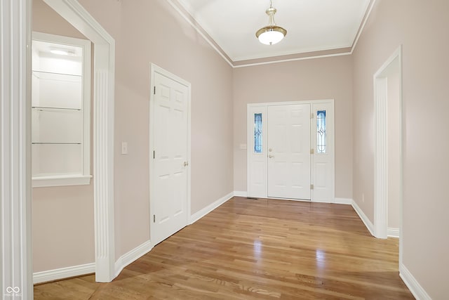 entrance foyer with light wood-type flooring, baseboards, and ornamental molding