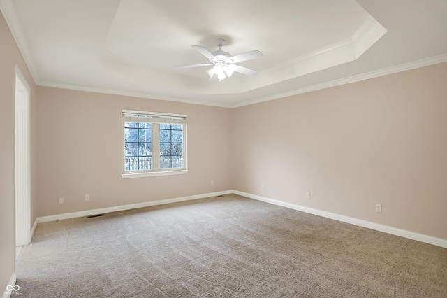 carpeted empty room with baseboards, a tray ceiling, ceiling fan, and crown molding