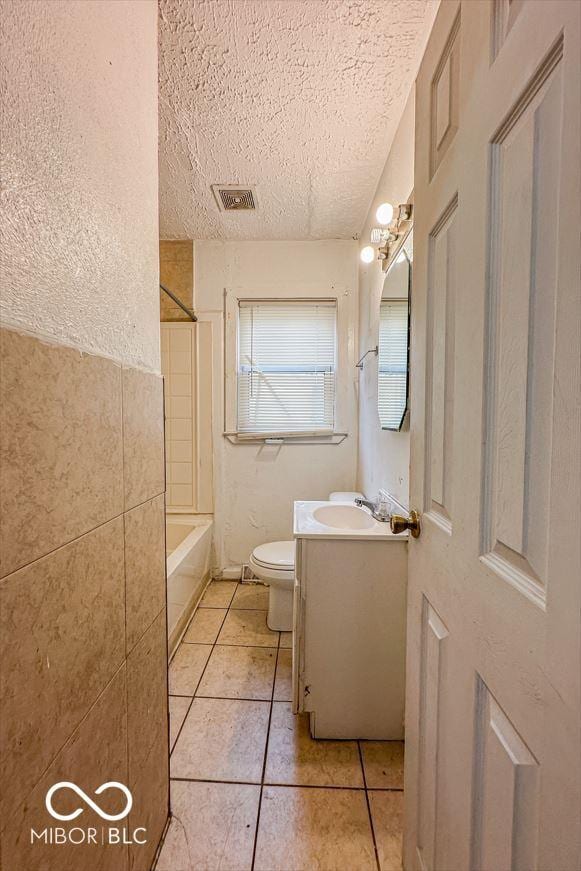 bathroom featuring visible vents, toilet, a textured ceiling, vanity, and shower / bathing tub combination