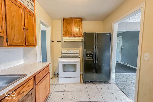 kitchen with black fridge with ice dispenser, brown cabinets, white electric range, under cabinet range hood, and backsplash