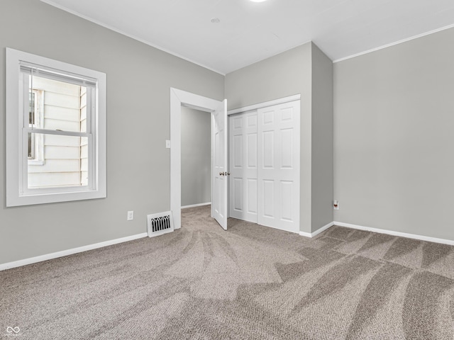 unfurnished bedroom featuring carpet floors, a closet, and crown molding