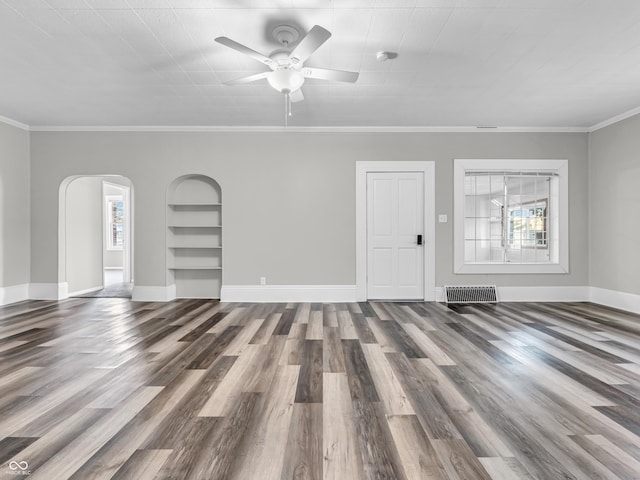 unfurnished living room with crown molding, hardwood / wood-style flooring, built in shelves, and ceiling fan