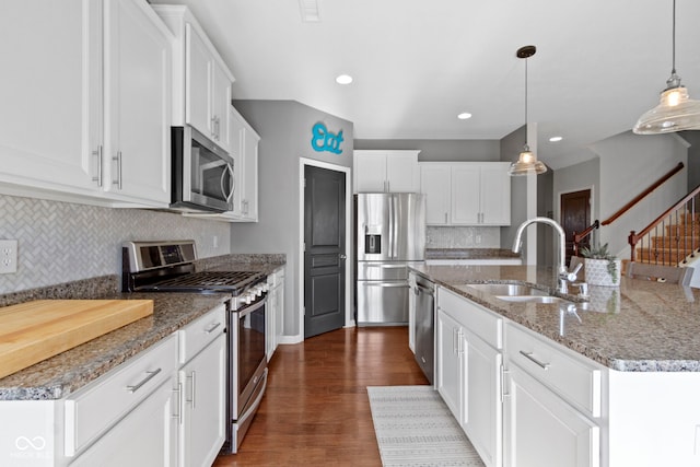 kitchen with an island with sink, a sink, dark wood-style floors, stainless steel appliances, and white cabinets