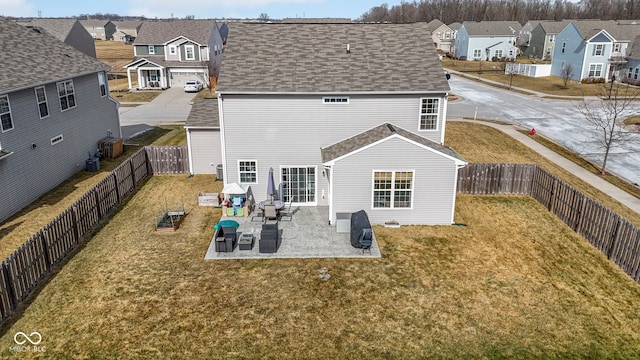 back of property with a fenced backyard, a residential view, a lawn, and a patio