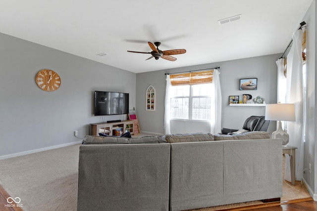 carpeted living room featuring a ceiling fan, visible vents, and baseboards