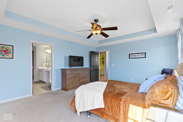 bedroom featuring visible vents, ensuite bathroom, a tray ceiling, baseboards, and light colored carpet