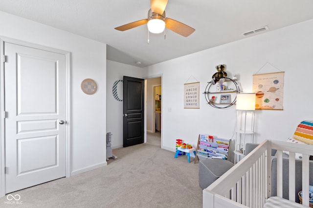 carpeted bedroom with visible vents, ceiling fan, baseboards, and a nursery area