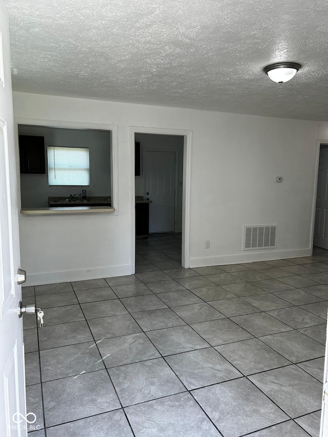 unfurnished room featuring tile patterned floors and a textured ceiling