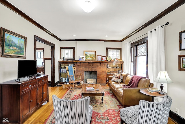 living room with baseboards, ornamental molding, light wood-type flooring, and a brick fireplace