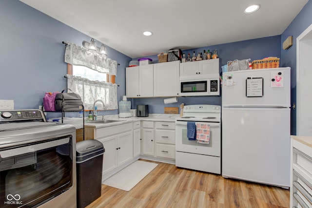 kitchen featuring white appliances, sink, white cabinetry, light hardwood / wood-style floors, and washer / clothes dryer