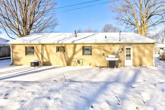 snow covered back of property featuring central AC