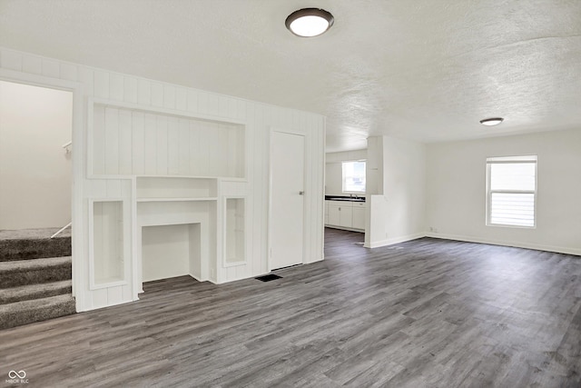 952 N Concord St, Indianapolis, IN 46222 - unfurnished living room with dark wood-style floors, healthy amount of natural light, stairway, and a textured ceiling
