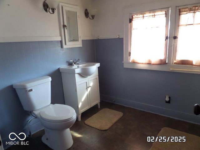 bathroom featuring toilet, tile walls, and vanity