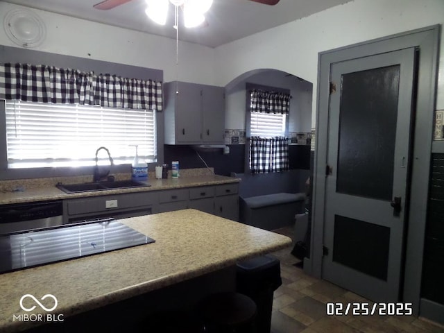 kitchen featuring light countertops, stainless steel dishwasher, a sink, and a healthy amount of sunlight