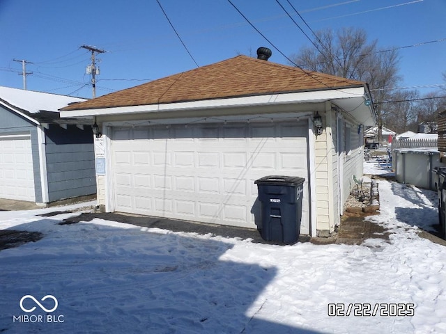 snow covered garage with a detached garage