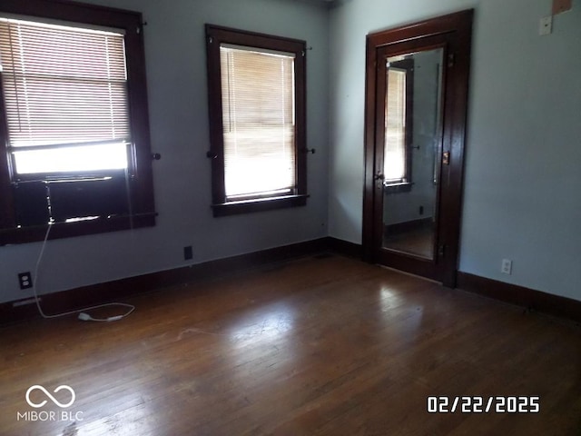 empty room featuring dark wood-style floors and baseboards