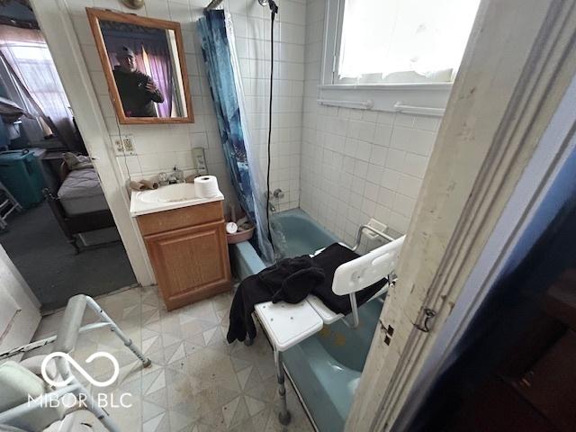 bathroom featuring vanity, shower / bath combination with curtain, and tile walls