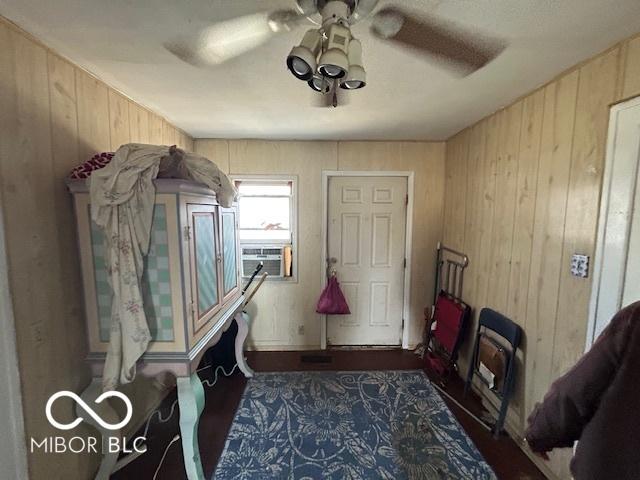 interior space with cooling unit, ceiling fan, and wood walls