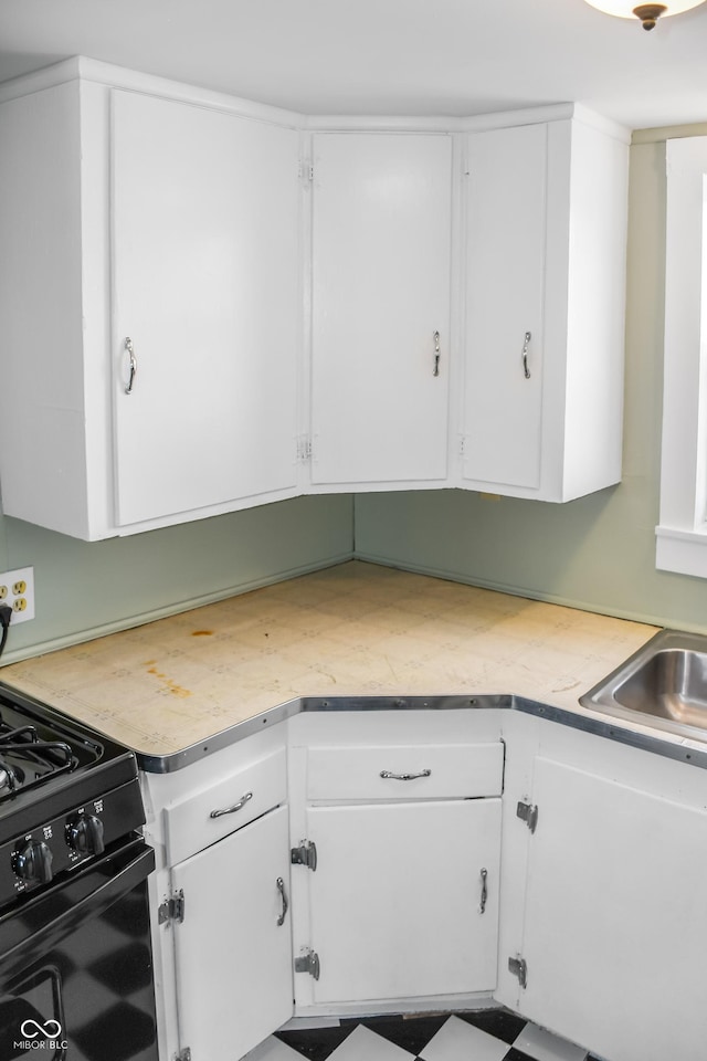 kitchen with white cabinetry, black range with gas cooktop, and sink