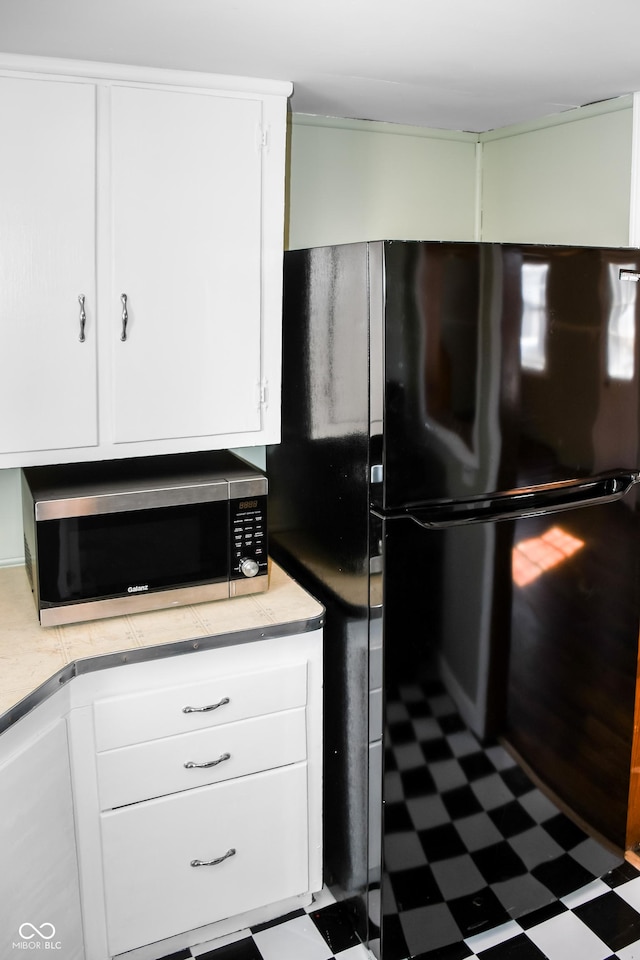 kitchen with black refrigerator and white cabinets