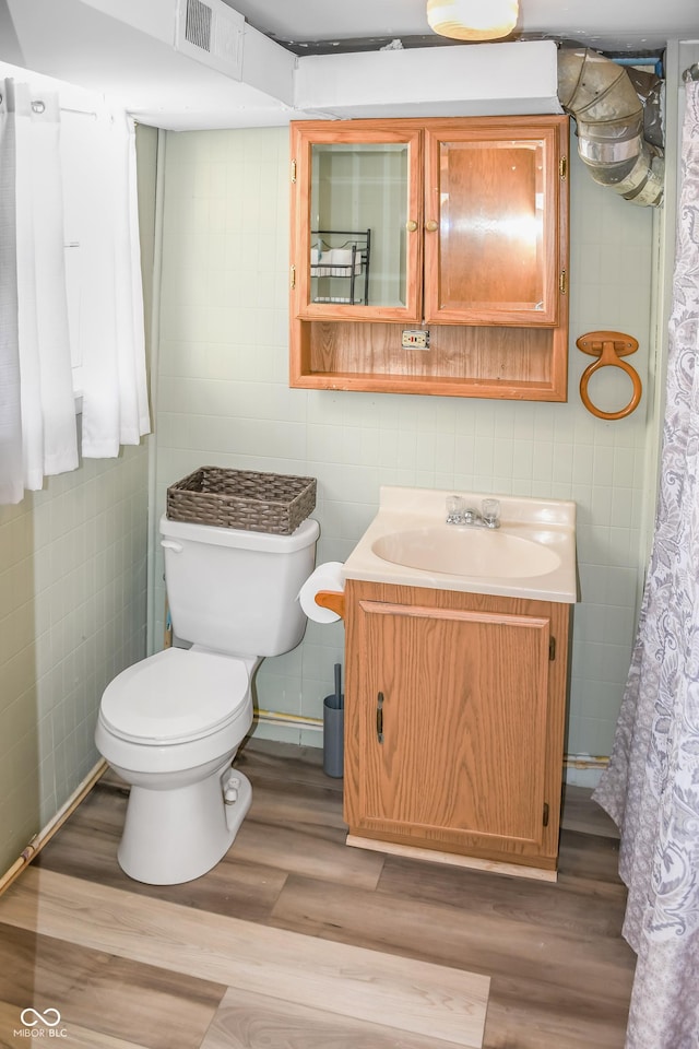 bathroom with vanity, toilet, hardwood / wood-style floors, and tile walls