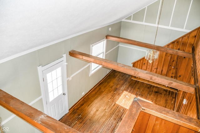 stairway with hardwood / wood-style flooring, lofted ceiling, and an inviting chandelier