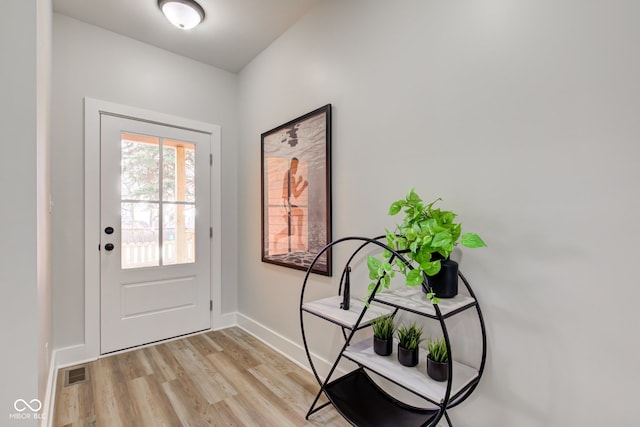 doorway featuring light wood-style flooring, visible vents, and baseboards