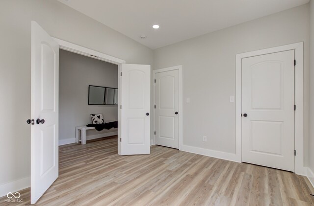 unfurnished bedroom with recessed lighting, light wood-style flooring, and baseboards