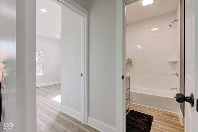 bathroom featuring baseboards, tub / shower combination, and wood finished floors