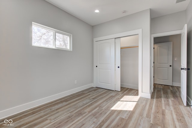 unfurnished bedroom featuring a closet, light wood-type flooring, and baseboards