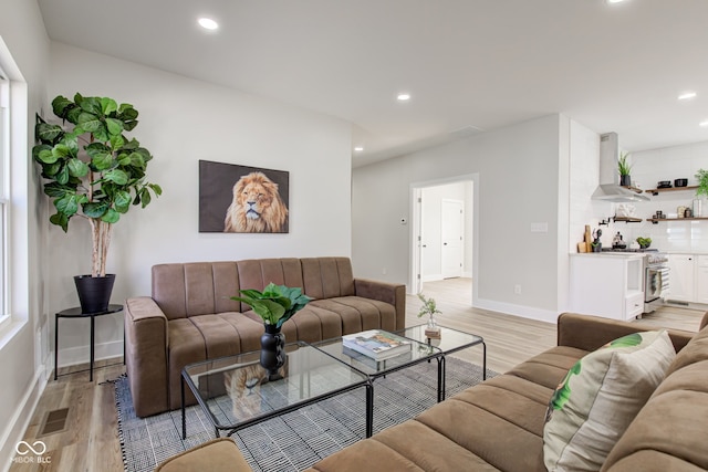 living room featuring light wood-style floors, recessed lighting, visible vents, and baseboards